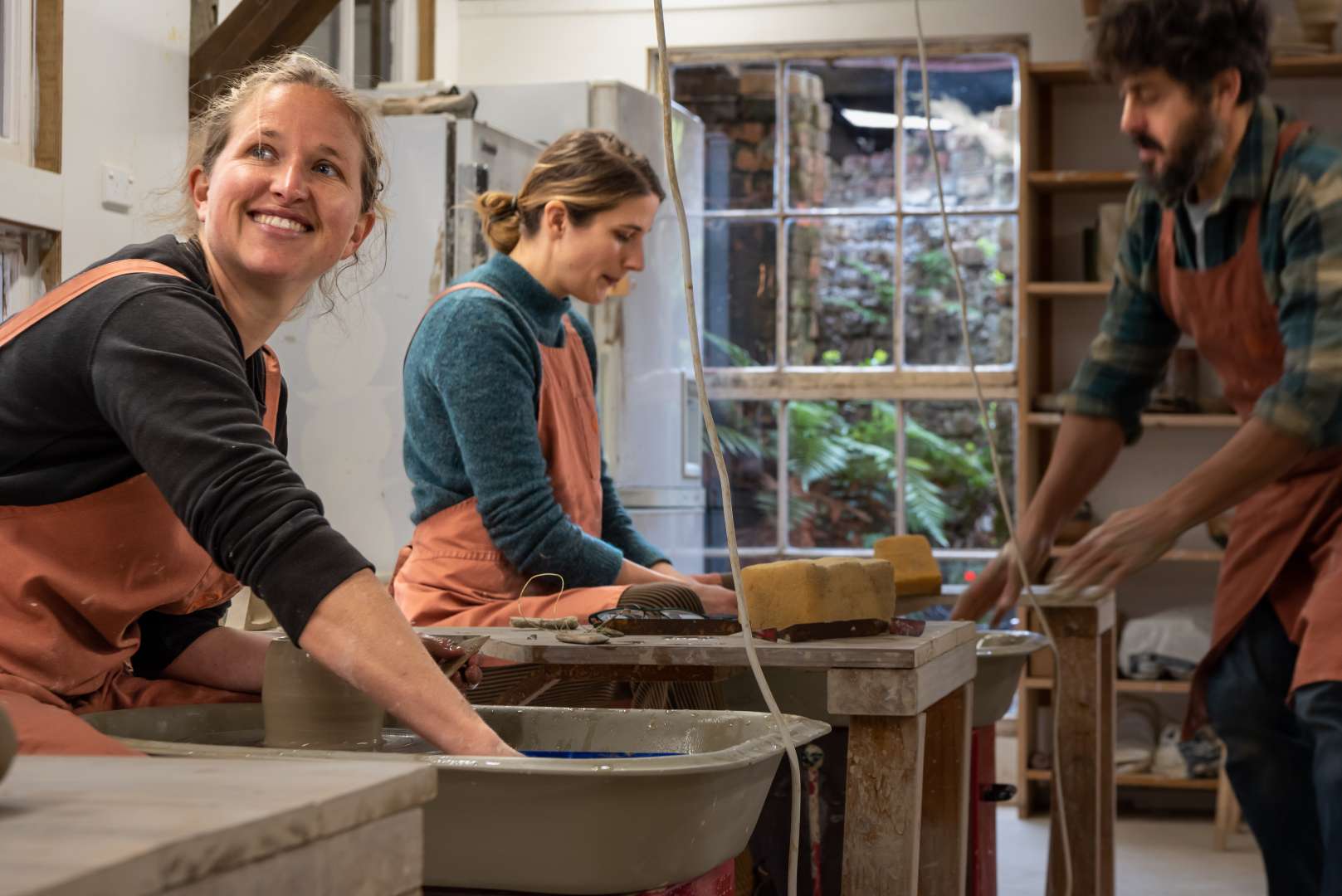 Smiling visitors at the pottery wheel